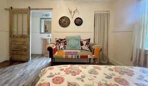 A bedroom with a bed, a sofa, a mirror, a wall-mounted deer skull, and a door. - Lazy Aker Nest-river front, family fun, cold pool, stars, picnic, gatherings (Franklinton)