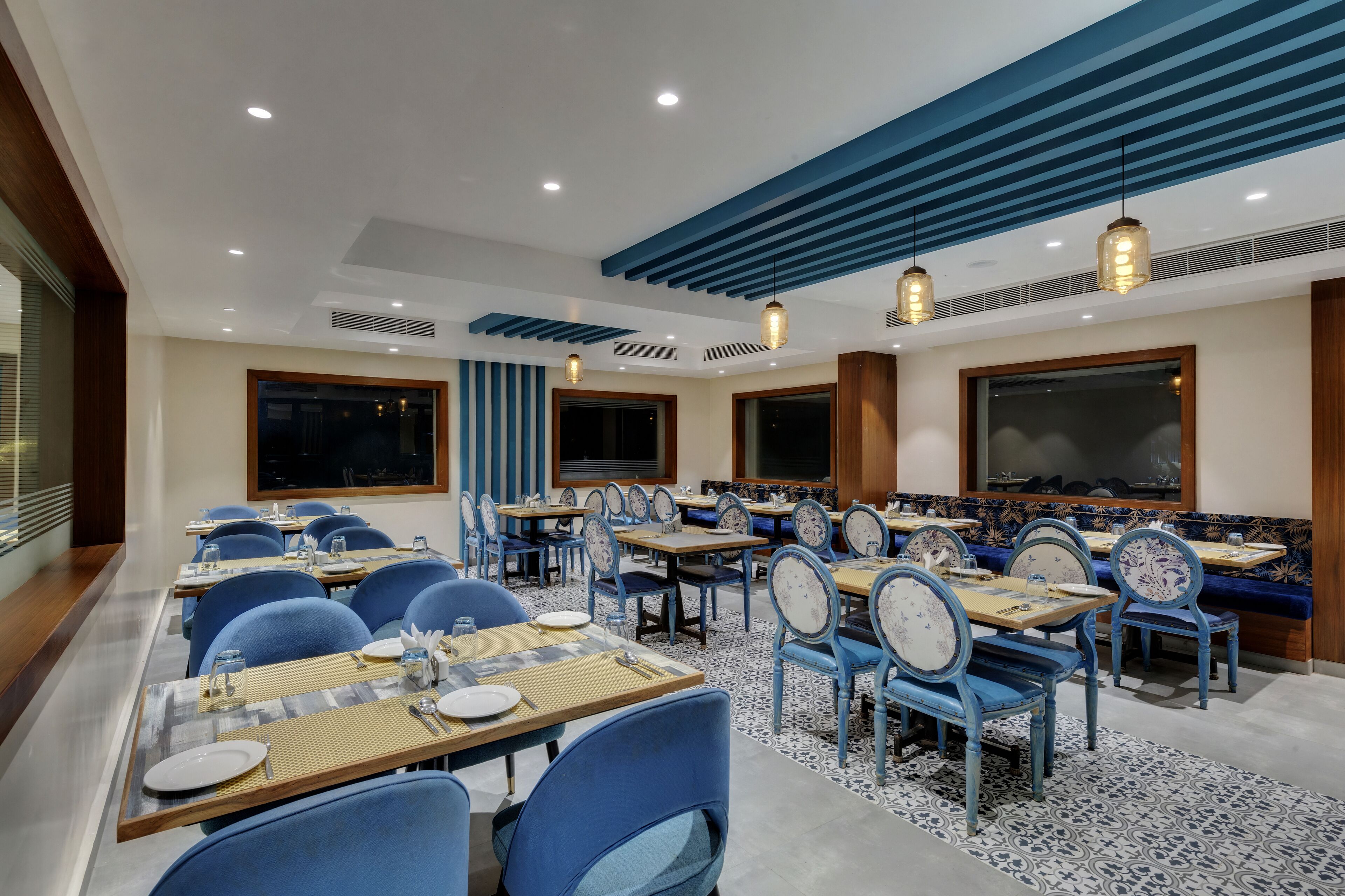 Un restaurante con sillas azules, mesas de madera y un suelo estampado.