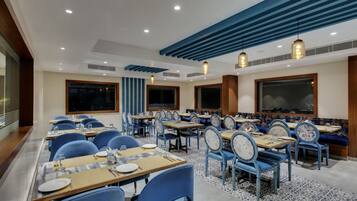Un restaurante con sillas azules, mesas de madera y un suelo estampado.