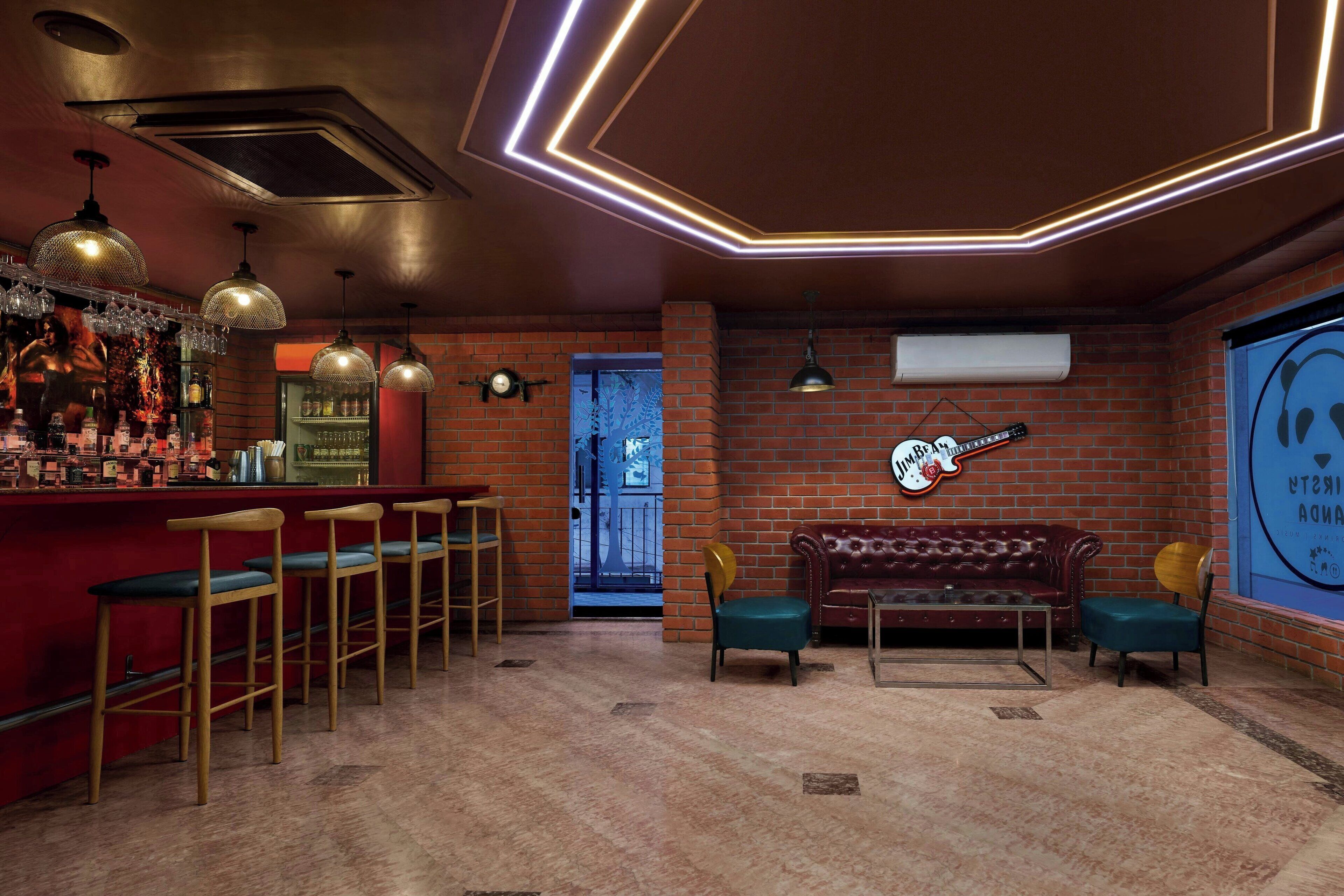 A bar area with stools, a red counter, and hanging lights.
