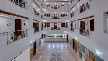 A multi-level hotel lobby with a central open space, multiple balconies, and a polished marble floor.