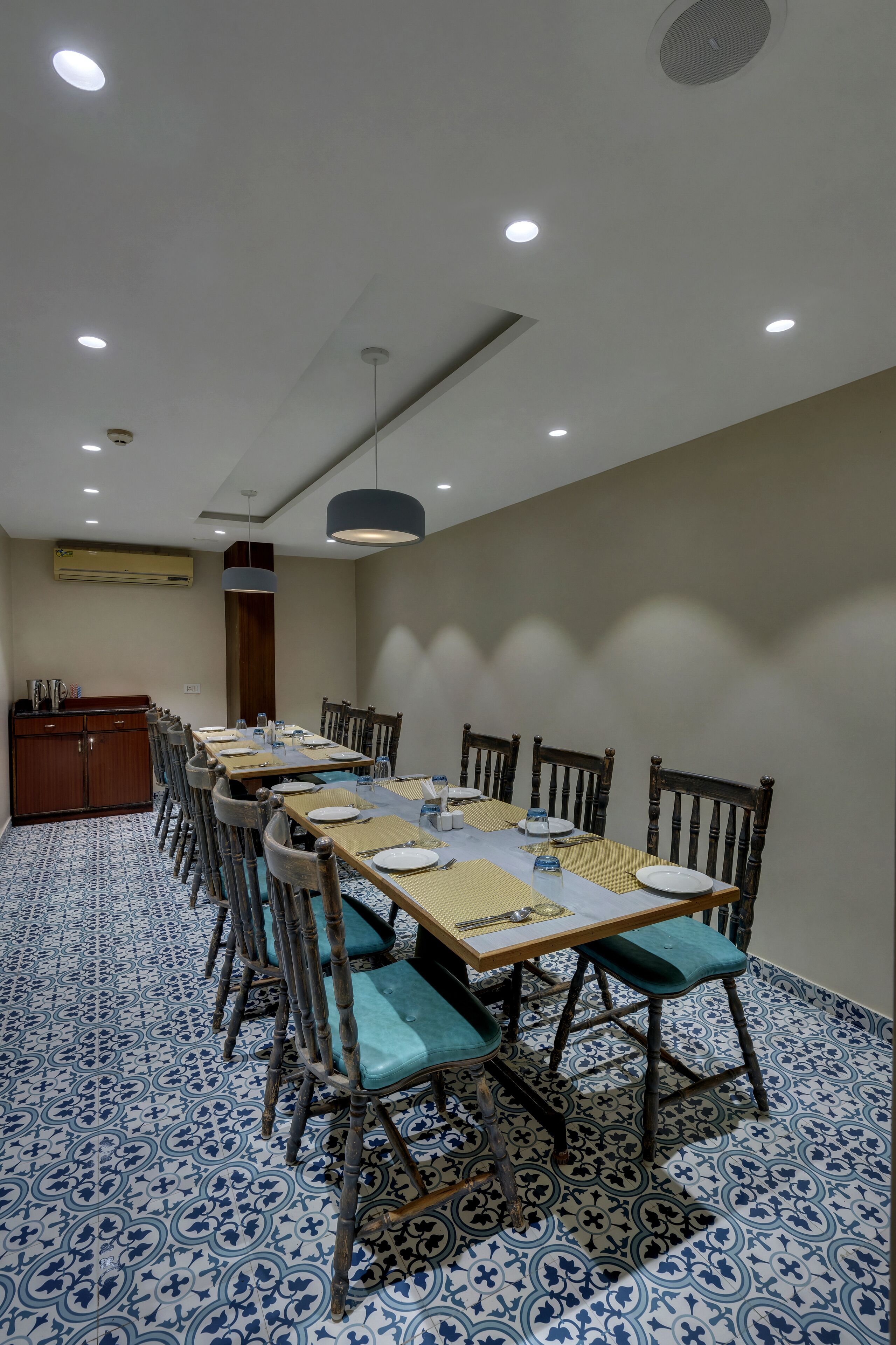 A dining area with a long table, chairs, and a ceiling light fixture.