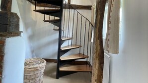 A rustic staircase with wooden steps and metal railings, leading to an upper floor. - Bere Cottage (Canterbury)