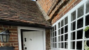 A white door with the number 35, a small window with white frames, and a brick wall. - Bere Cottage (Canterbury)