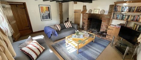 A cozy living room with a sofa, a coffee table, a fireplace, and a bookshelf.