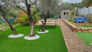 A well-maintained garden with a paved pathway, a small shed, and a picnic table. - Charming stone-built 2-person apartment, in a quiet location with pool access.  (Lorgues)