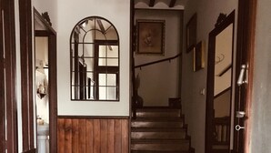 A hallway with wooden paneling, a patterned carpet, a staircase, and a mirror on the wall.