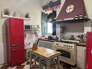 Una cocina con un refrigerador rojo, una estufa blanca y una mesa de madera con sillas.
