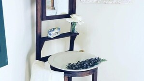 A bathroom with a white sink, a mirror, and a decorative vase with white flowers.