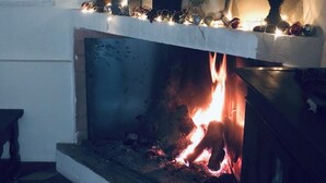 A fireplace with a stone mantle, lit fire, and decorative items.