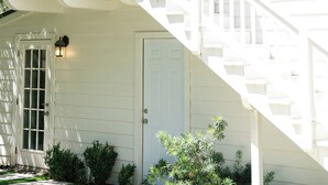 Une maison à deux étages, à l’extérieur blanc, dotée d’un porche à l’avant et d’un escalier menant au deuxième étage.