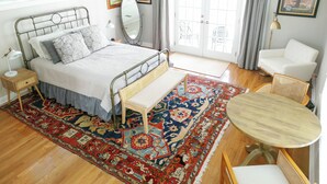 Une chambre à coucher avec un lit, une table de chevet, une lampe et une grande fenêtre.