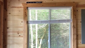 A room with a large window, a wooden bench, and a metal table. - Sunset Hillside Cabin staycation on Horse Farm - Pet Friendly D (Fayetteville)