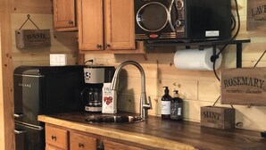 A kitchen with wooden cabinets, a black refrigerator, a coffee maker, and a microwave. - Sunset Hillside Cabin staycation on Horse Farm - Pet Friendly D (Fayetteville)