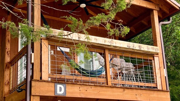 A wooden cabin with a balcony, a hammock, and a ceiling fan. - Sunset Hillside Cabin staycation on Horse Farm - Pet Friendly D (Fayetteville)