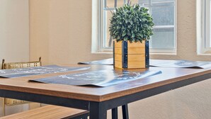 Una mesa de madera con una planta en maceta, tapetes negros y una ventana con vistas.