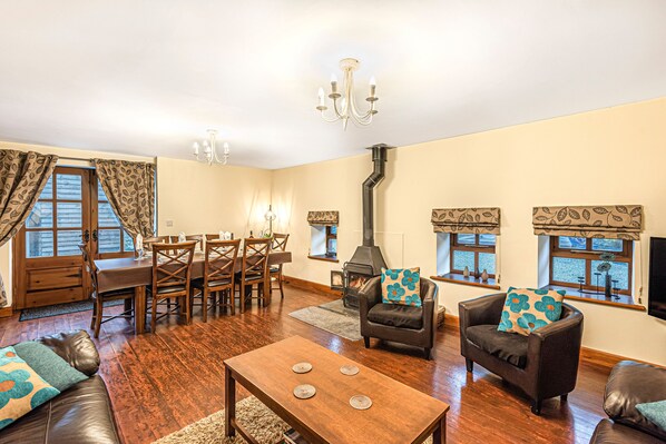 A cozy living room with a fireplace, wooden furniture, and a chandelier.