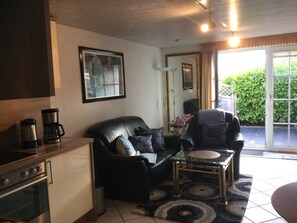 A compact living space with a kitchenette, a sofa, a coffee table, and a chair.
