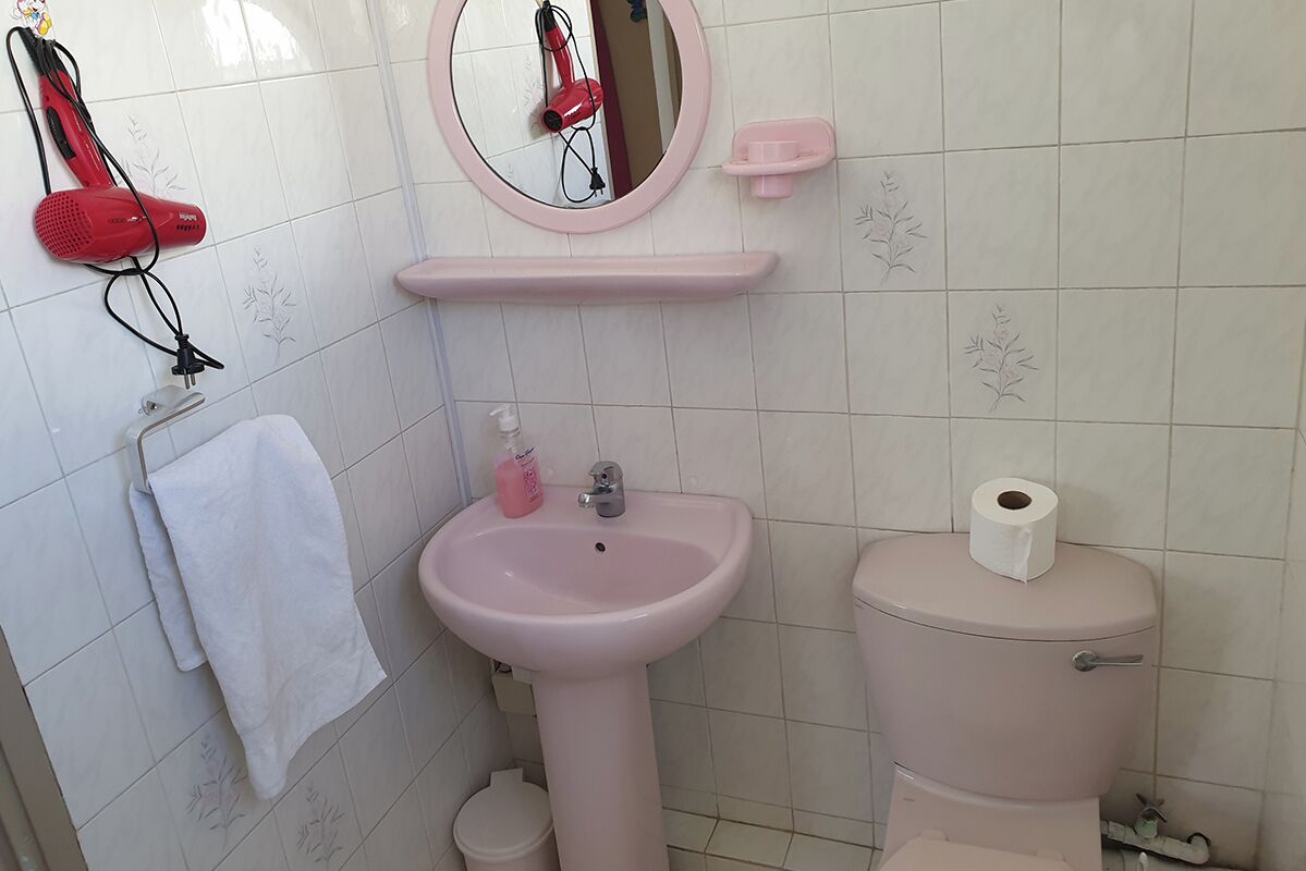 A bathroom with a pink sink, toilet, and towel rack.