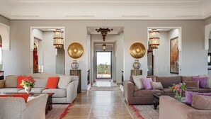 A spacious living room with two sofas, a coffee table, and decorative lamps. - Villa Le Clos des Oliviers (Marrakech Alentours)