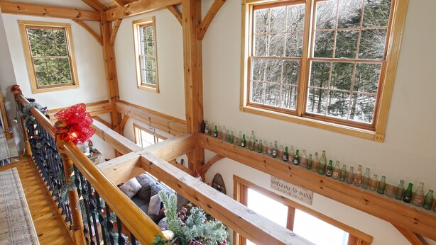 A wooden interior with a staircase, a Christmas tree, and a shelf with bottles. - Secluded, Cozy Cabin on 10 Acres of Woods ~16 mi to Slopes & Pet Friendly! (Whitingham)