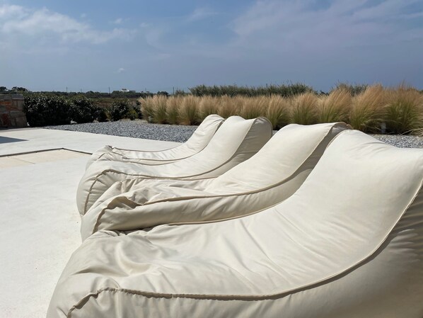 A row of white lounge chairs with a view of a landscaped garden and distant buildings.