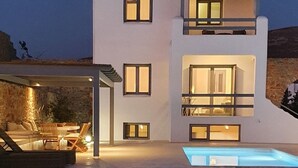 En moderne bygning med to etager, en pool, udendørs siddepladser og en overdækket patio.