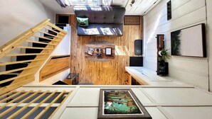 A modern interior with a wooden staircase, a small seating area with a rug, and a framed picture on the floor. - The Davis Loft - Perfect Location (Davis)