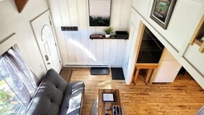 A modern loft-style living space with a loft bed, a sofa, a coffee table, and a kitchen area. - The Davis Loft - Perfect Location (Davis)