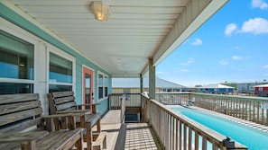 A covered outdoor area with wooden benches, a pool, and a view of other buildings.