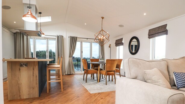 A spacious living area with a wooden floor, a beige sofa, and a dining table with chairs. - Henry Haven (Preston)