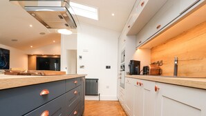 A modern kitchen with a central island, wooden countertop, and stainless steel appliances. - Henry Haven (Preston)