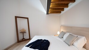 Un dormitorio con cama, cabecero de madera, mesita de noche con lámpara y espejo en la pared.