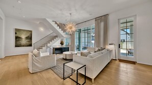 Ein geräumiges Wohnzimmer mit moderner Treppe, großem Fenster und minimalistischem Design.