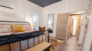 Un dormitorio con cama, un banco, un espejo y un armario.
