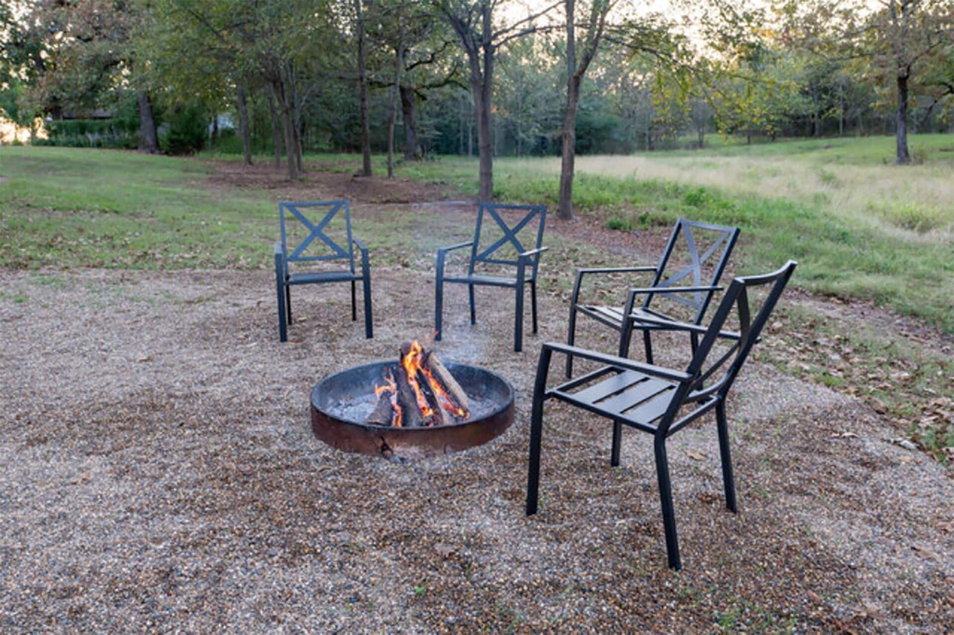 A fire pit with four chairs arranged around it in an outdoor setting.