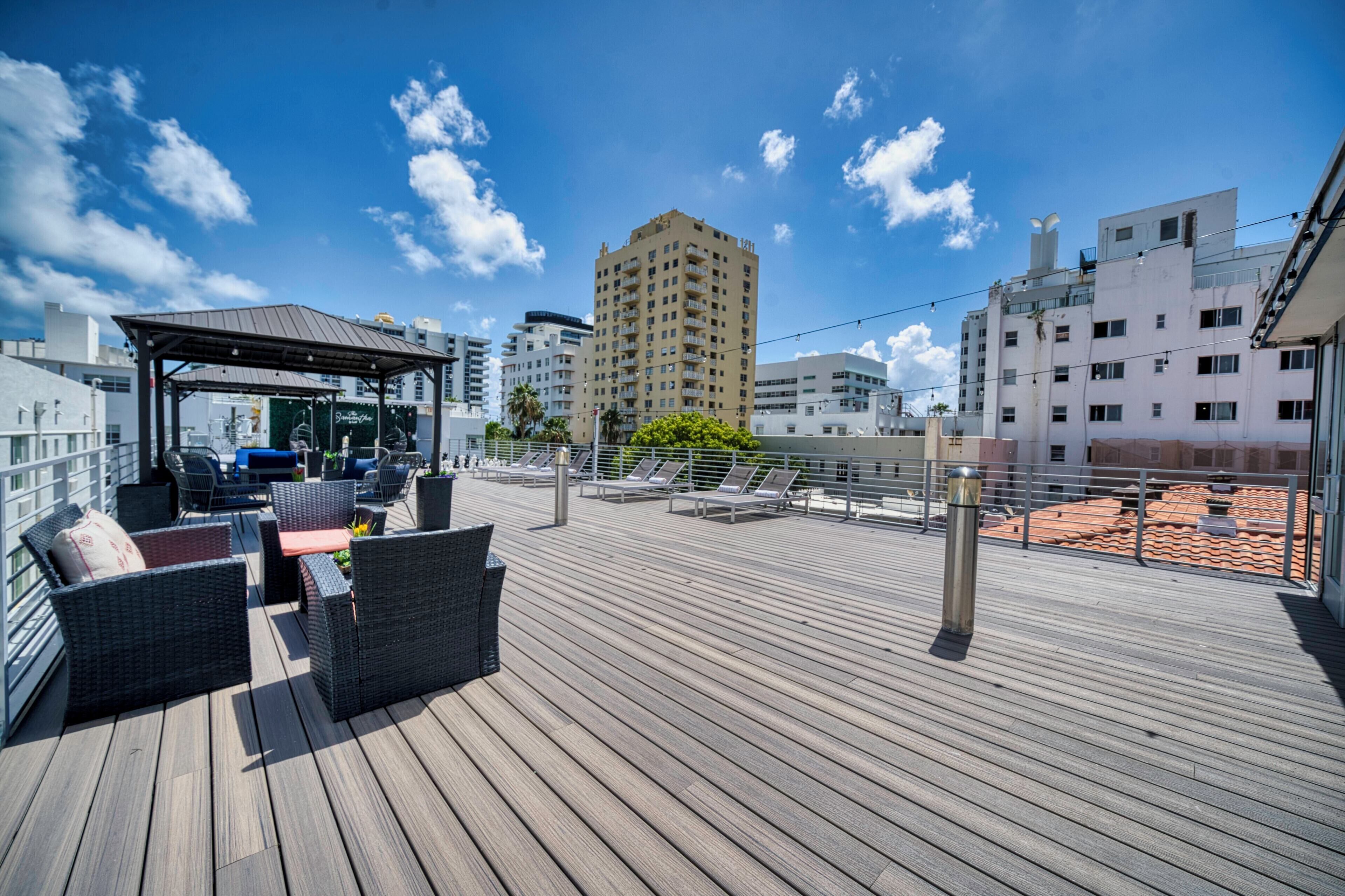 A rooftop deck with outdoor furniture, a covered seating area, and a view of surrounding buildings.