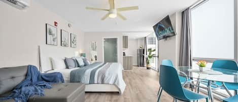 Ein modernes Hotelzimmer mit Bett, Sofa, Esstisch, Stühlen und einem Fernseher.