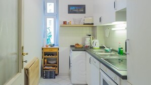 A compact kitchen with a built-in oven, a coffee maker, and a sink. - fully furnished 2-room apartment in Berlin (Berlin)