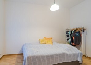 Une chambre à coucher avec un lit, un luminaire suspendu et un portant à vêtements.