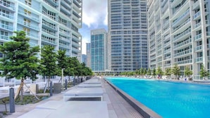 A modern poolside area with lounge chairs and a clear blue pool, surrounded by high-rise buildings. - ICON W BRICKELL COZY CITY VIEW 1BR/1BA/DEN (Miami)