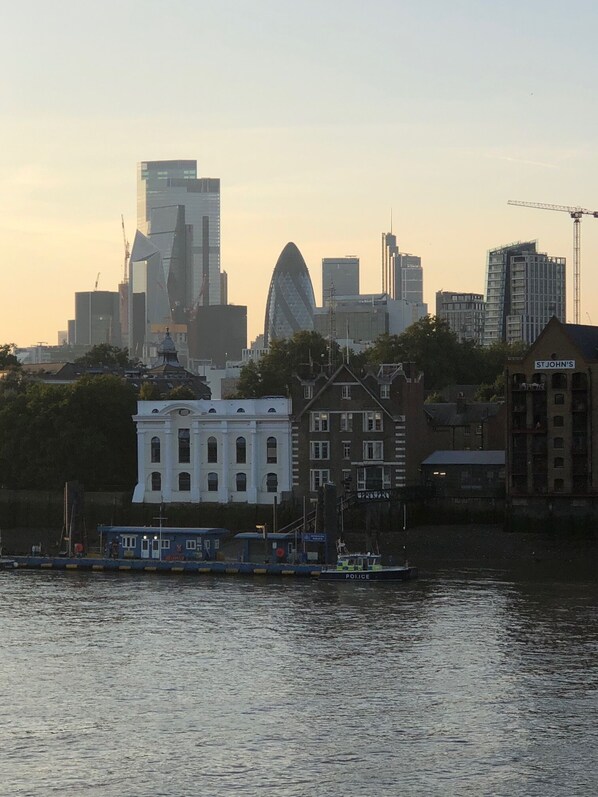 A city skyline with modern buildings, a police boat, and a historic white building with arched windows. - Riverside Penthouse Apartment (London)