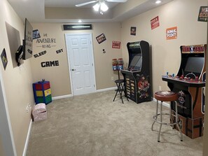 Relax in a room designed for adventure, featuring arcade machines and a cozy seating area.