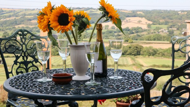 A round table with a white vase, four wine glasses, and a bottle of champagne.