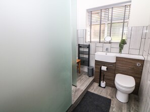 A modern bathroom with a toilet, sink, and window with blinds. - The Bungalow@barlow (Dronfield)