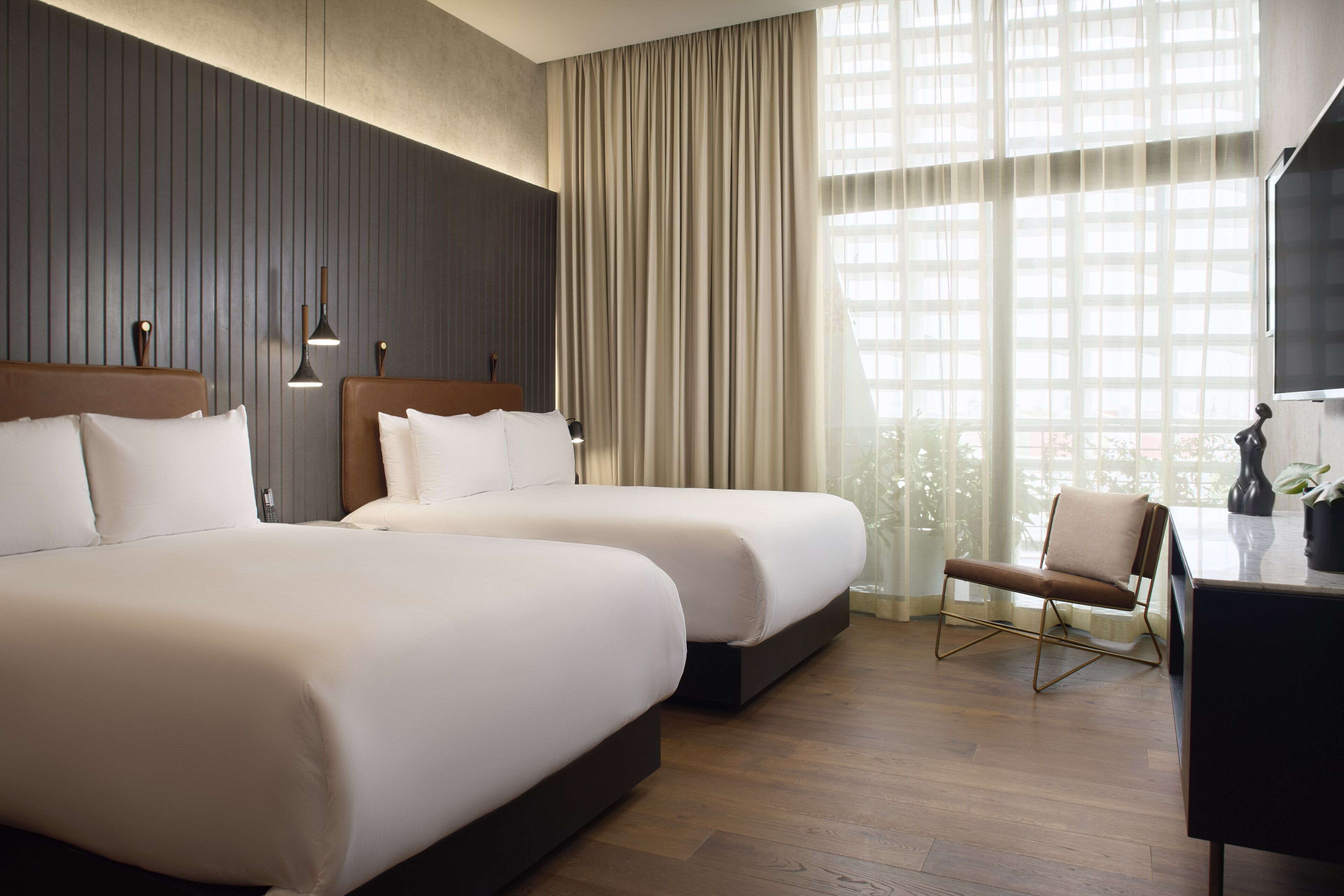 A hotel room with two beds, a desk, and a chair.