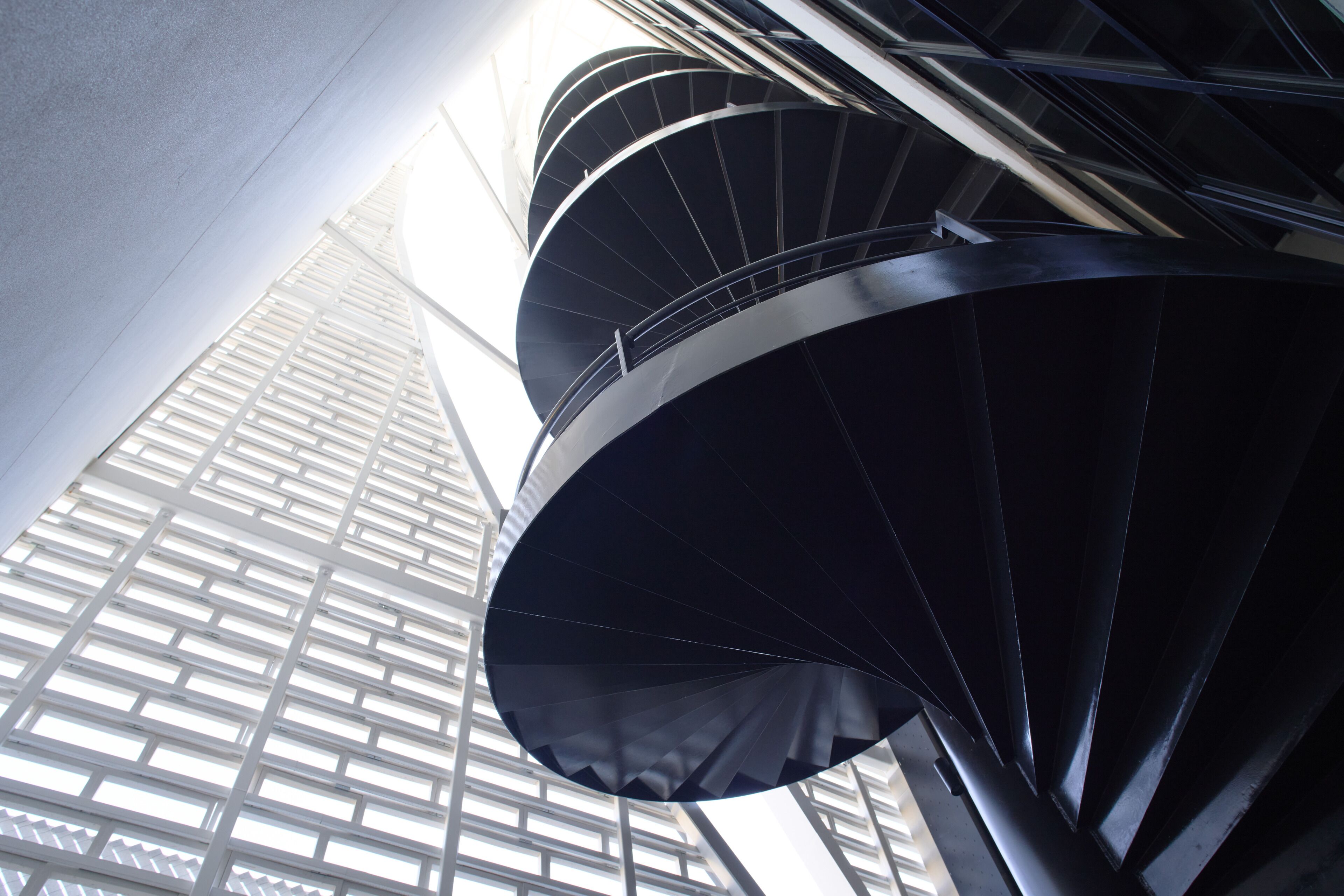 A spiral staircase with a modern design, surrounded by a grid-like structure.