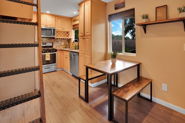 A kitchen with wooden cabinets, a microwave, oven, and a dining table with benches.