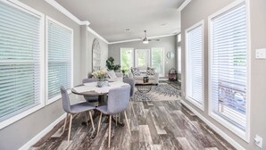 A dining area with a round table, gray chairs, and a decorative centerpiece. - The Lantana Tiny Home  ~ Cottage in the Woods ~ NEW HOT TUB & DOGGY PLAY YARD (Willis)