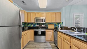 A kitchen with wooden cabinets, stainless steel appliances, and a tiled backsplash.